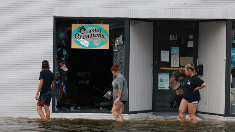 La gente camina en las aguas de inundación más allá de una tienda que tiene una ventana rota después de que el huracán Idalia pasó mar adentro el 30 de agosto de 2023 en Crystal River, Florida. (Joe Raedle/Getty Images)