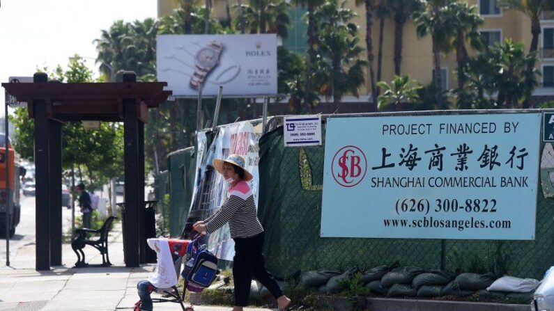 Una mujer empuja una carriola frente a una pancarta en un proyecto de construcción financiado por el Banco Comercial de Shanghái en San Gabriel, California, el 17 de mayo de 2016. (Frederic J. Brown /AFP/Getty Images)