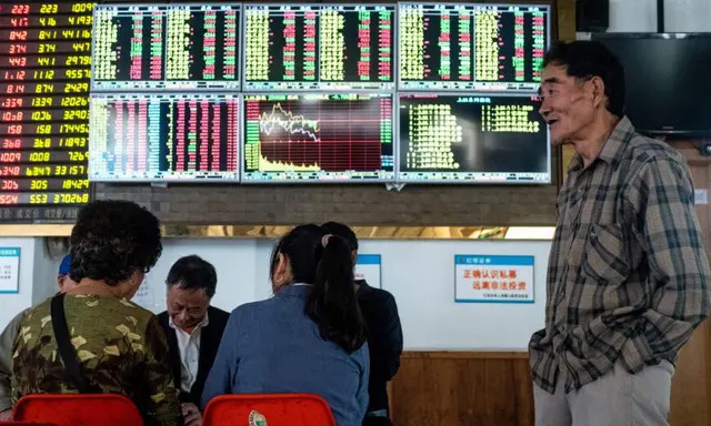 Un inversor mira un tablero electrónico que muestra información bursátil en una casa de bolsa en Shanghái, China, el 15 de octubre de 2018. (Johannes Eisele/AFP vía Getty Images)