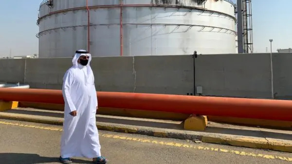 Un hombre, cubierto con una mascarilla debido a la pandemia de COVID-19, pasa junto a un silo dañado en las instalaciones petrolíferas de Saudi Aramco en la ciudad saudí de Yedda, en el Mar Rojo, el 24 de noviembre de 2020. (Fayez Nureldine/AFP vía Getty Images)
