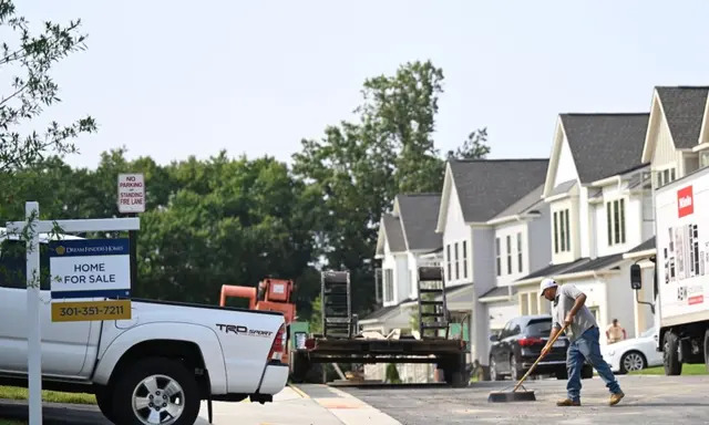 Se muestra un cartel de "se vende" delante de una casa nueva en una urbanización mientras un trabajador de mantenimiento barre la calle en Fairfax, Virginia, el 22 de agosto de 2023. (Andrew Caballero-Reynolds/AFP vía Getty Images)