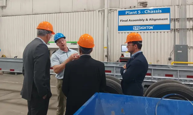 El representante Darin LaHood ( R-Ill.), el representante Mike Gallagher (R-Wis.) y el representante Raja Krishnamoorthi (D-Ill.) escuchan a Bob Wahlin, de Stoughton Trailers, durante una visita a una línea de producción de chasis en las instalaciones de la empresa en Stoughton, Wisconsin, el 30 de agosto de 2023. (Nathan Worcester/The Epoch Times)