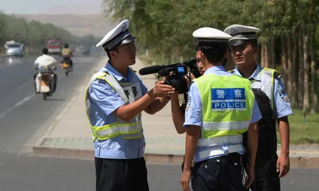La policía china detiene a un periodista en un puesto de control en la carretera que conduce a la ciudad uigur de Lukqun, provincia de Xinjiang, afectada por disturbios, el 28 de junio de 2013. (Mark Ralston/AFP vía Getty Images)