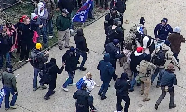 Un grupo de manifestantes transporta a Benjamin J. Philips en una camilla improvisada después de que los paramédicos se negaran a acudir al lugar donde se desplomó, cerca del Capitolio de EE.UU., el 6 de enero de 2021. (Policía del Capitolio de EE.UU./Screenshot vía The Epoch Times)