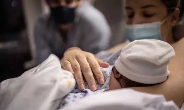 Un padre y una madre miran a su hijo recién nacido en la maternidad del hospital de las Diaconisas de París, el 17 de noviembre de 2020. (Martin Bureau/AFP vía Getty Images)