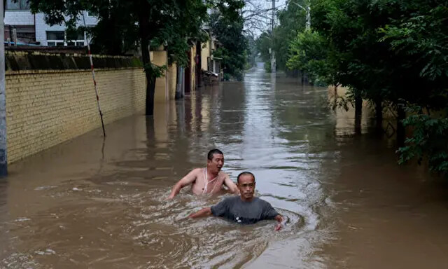 Residentes locales luchan en aguas profundas y rápidas mientras se dirigen hacia los rescatistas en un bote, en un área inundada cerca de Zhuozhou, provincia de Hebei, al sur de Beijing, el 3 de agosto de 2023. (Kevin Frayer/Getty Images)

