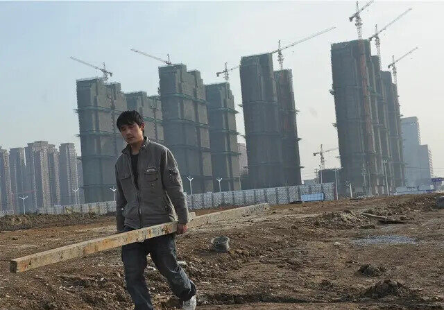 Un obrero transporta materiales en el lugar de construcción de un nuevo proyecto de viviendas en Hefei, en la provincia oriental china de Anhui, el 18 de febrero de 2012. El mercado inmobiliario, en auge antes de la recesión mundial, ha empeorado notablemente. (STR/AFP/Getty Images)