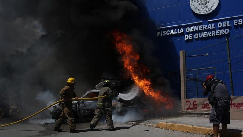 Bomberos trabajan en el control del incendio de un vehículo durante una manifiestan el 23 de septiembre de 2023, frente a la Fiscalía General del Estado para exigir justicia por los 43 normalistas desaparecidos de Ayotzinapa, en Chilpancingo, Guerrero (México). EFE/José Luis de la Cruz
