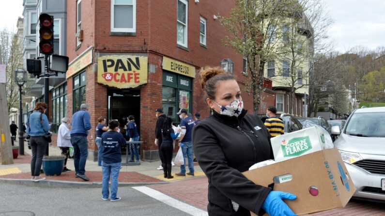 Una mujer cruza la calle mientras lleva paquetes de bienes donados de Chelsea Collaborative Inc. afuera del Pan y Cafe en Chelsea, Massachusetts, el 14 de abril de 2020. (JOSEPH PREZIOSO/AFP vía Getty Images)