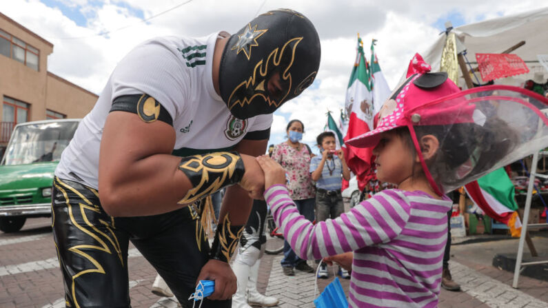 Una niña saluda al luchador mexicano de Lucha Libre Ciclónico, el 03 de septiembre de 2020 en Xochimilco, México. (Hector Vivas/Getty Images)