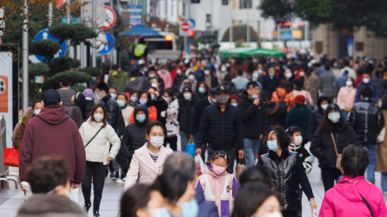 Personas con mascarillas protectoras caminan por Shanghai el 11 de diciembre de 2022. (Hu Chengwei/Getty Images)