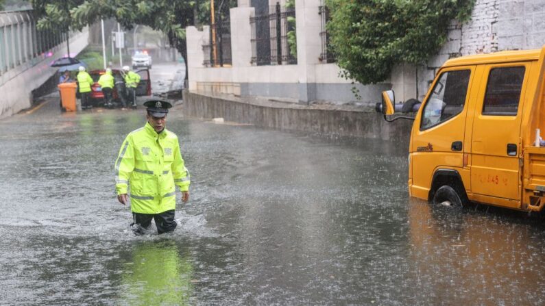 Un agente de policía camina por una calle inundada a causa de las fuertes lluvias tras la llegada a tierra del tifón Doksuri en Xiamen, en la provincia oriental china de Fujian, el 28 de julio de 2023. (STR/AFP vía Getty Images)