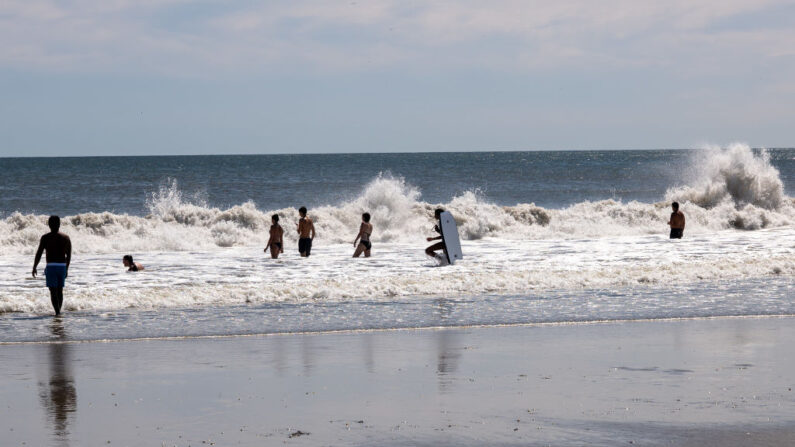 La gente disfruta de un día en la playa de Rockaway en Nueva York, mientras el fuerte oleaje del huracán Franklin provoca fuertes mareas y grandes olas en la mayor parte de la costa este el 31 de agosto de 2023 en la ciudad de Nueva York. (Spencer Platt/Getty Images)