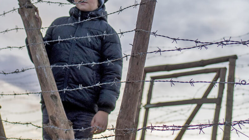 Un niño eslovaco de siete años, lleva un sombrero militar soviético mientras permanece junto a los restos de las vallas fronterizas de la antigua "Cortina de Hierro " entre Eslovaquia y Austria el 20 de noviembre de 2016 cerca de Bratislava, Eslovaquia. (JOE KLAMAR/AFP via Getty Images)