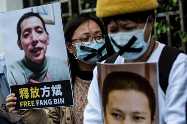 Una activista prodemocracia (C) de HK Alliance sostiene una pancarta del periodista ciudadano desaparecido Fang Bin, mientras protesta ante la oficina de enlace china en Hong Kong el 19 de febrero de 2020. (Isaac Lawrence/AFP vía Getty Images)