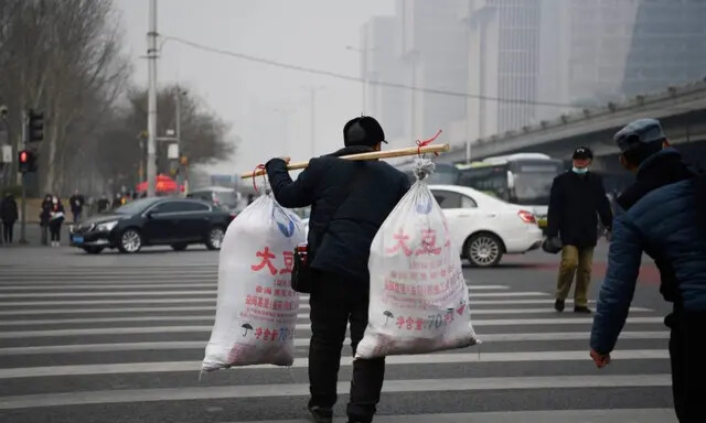 Un trabajador migrante cruza una carretera tras llegar en un autobús de larga distancia en Pekín el 10 de marzo de 2021. (Greg Baker/AFP vía Getty Images)