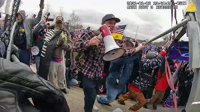 Sean Michael McHugh de Auburn, California, sostiene un megáfono mientras ayuda a empujar una pancarta de Donald Trump hacia una línea policial en el Capitolio de EE.UU., el 6 de enero de 2021. (Departamento de Policía Metropolitana/Captura de pantalla vía The Epoch Times)
