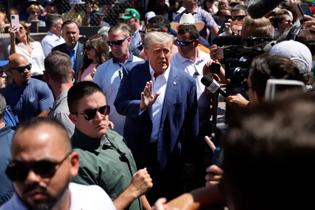 Rodeado por el personal de campaña y miembros del Servicio Secreto de EE.UU., el expresidente de Donald Trump (centro) saluda a sus partidarios mientras visita la carpa de los productores de carne de cerdo de Iowa, en la Feria Estatal de Iowa, en Des Moines, Iowa, el 12 de agosto de 2023. (Chip Somodevilla/Getty Images)