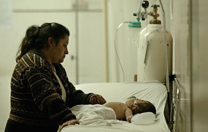 Una mujer mira a su bebé en el hospital público infantil de Santiago, tras un agresivo brote del virus sincicial, el más grave de la última década, el 09 de julio de 2004 en Chile. (VICTOR ROJAS/AFP via Getty Images)