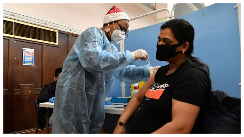Una trabajadora de la salud administra una dosis de la vacuna contra COVID-19 a una mujer embarazada en un centro de vacunación improvisado en el Ayuntamiento de Redbridge, al este de Londres, el 25 de diciembre de 2021. (Justin Tallis/AFP vía Getty Images)