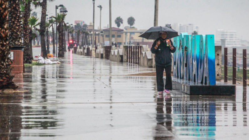 Una persona camina bajo la lluvia en el puerto de Ensenada en Baja California, México. Fotografía de archivo. (EFE/Alejandro Zepeda)