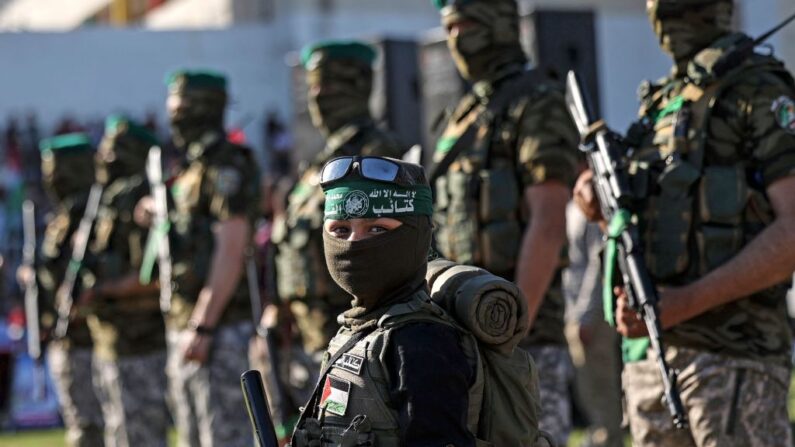 Un niño palestino está de pie con miembros de las Brigadas al-Qassam, el brazo armado del movimiento Hamás, durante una manifestación en la ciudad de Gaza el 24 de mayo de 2021. (Mahmud Hams/AFP vía Getty Images)