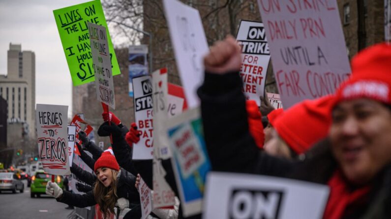 Enfermeras gritan consignas y sostienen pancartas mientras protestan contra los bajos salarios y los niveles de dotación de personal, durante una huelga frente al hospital Mount Sinai en Nueva York (EE.UU.) el 10 de enero de 2022. (Ed Jones/AFP vía Getty Images)
