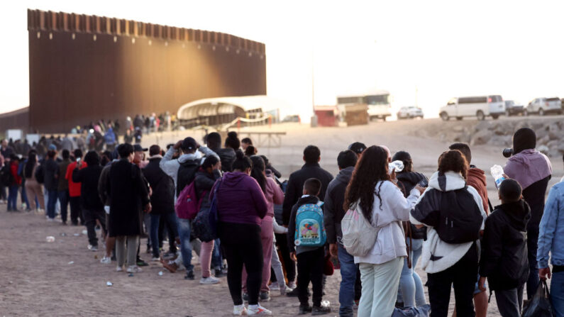 Una foto de archivo de inmigrantes que solicitan asilo en Estados Unidos esperan en fila para ser procesados por agentes de la Patrulla Fronteriza estadounidense desde México el 11 de mayo de 2023 en Yuma, Arizona. (Mario Tama/Getty Images)