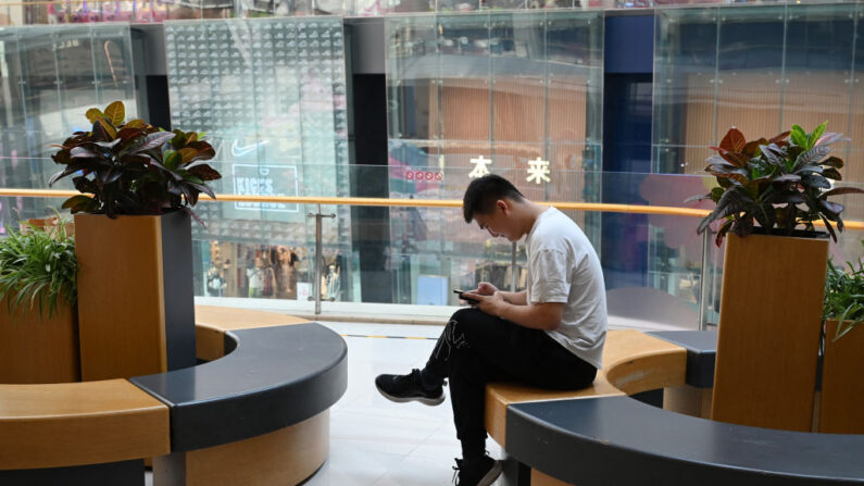 Un hombre consulta su teléfono mientras descansa en un centro comercial de Beijing el 18 de julio de 2023. (Greg Baker/AFP vía Getty Images)