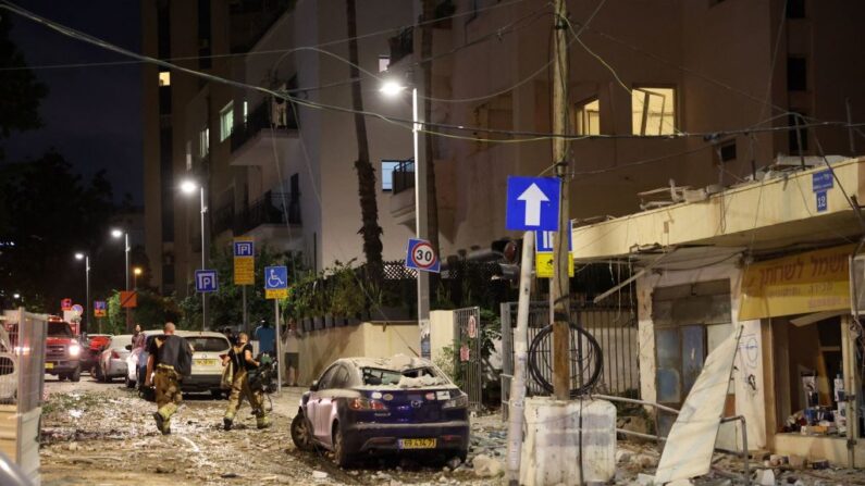 Miembros de las fuerzas de seguridad israelíes caminan por una calle de Tel Aviv sembrada de escombros tras el impacto de un cohete lanzado por militantes palestinos desde la Franja de Gaza, el 7 de octubre de 2023. (Jack Guez/AFP vía Getty Images)