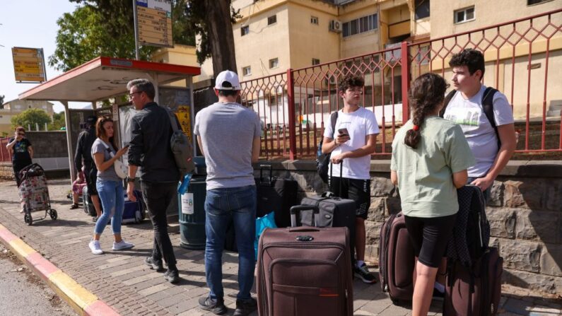 Personas con su equipaje esperan en una parada de autobús en la ciudad de Kiryat Shmona, en el norte de Israel, en la frontera con Líbano, para ser evacuadas a un lugar más seguro, el 22 de octubre de 2023. (Jalaa Marey/AFP vía Getty Images)
