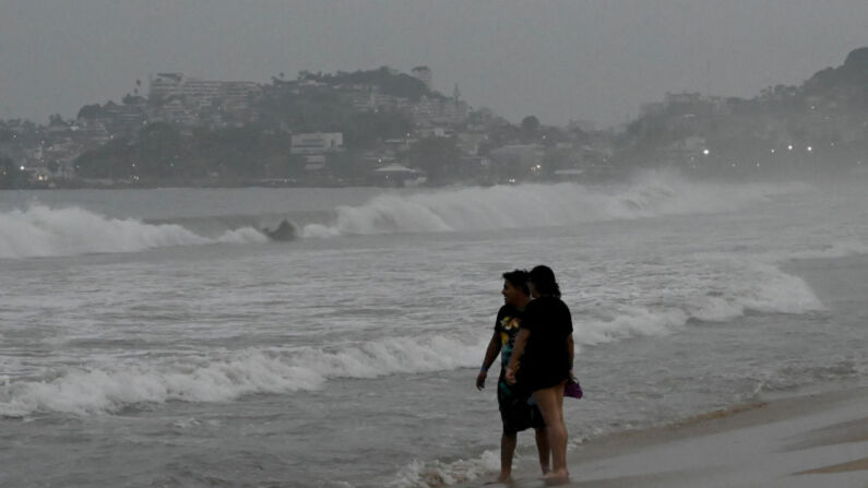La gente se para en la playa tras la alerta de llegada del huracán Otis en Acapulco, estado de Guerrero, México, el 24 de octubre de 2023. (FRANCISCO ROBLES/AFP vía Getty Images)