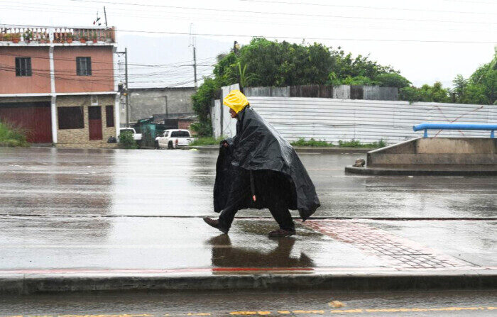 Un anciano cubierto con una bolsa de plástico camina por una calle de Tegucigalpa, Honduras, el 30 de octubre de 2023. Se prevee que la tormenta tropical "Pilar", formada en el océano Pacífico, tocará tierra mañana. (ORLANDO SIERRA/AFP via Getty Images)