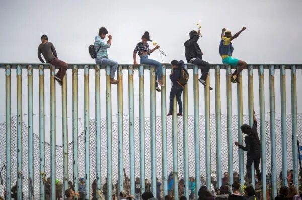 Inmigrantes ilegales escalan una sección de la valla fronteriza entre Estados Unidos y México en Tijuana, México, el 29 de abril de 2018. (David McNew/Getty Images)