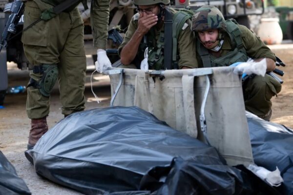 Un soldado de las FDI reacciona y se cubre la cara antes de retirar el cuerpo de un civil muerto días antes en un ataque de militantes de Hamás el 10 de octubre de 2023, en Kfar Aza, Israel. (Alexi J. Rosenfeld/Getty Images)