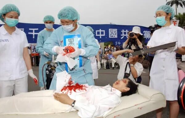 Practicantes de Falun Gong durante una representación de la práctica del PCCh de extracción forzosa de órganos a practicantes de Falun Gong, durante una manifestación en Taipei, Taiwán, el 23 de abril del 2006. (Patrick Lin/AFP vía Getty Images)