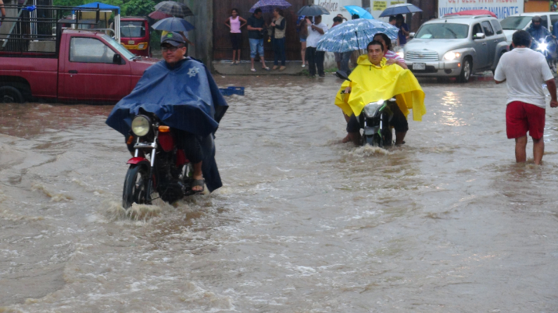 Fotografía de archivo de habitantes que transitan por calles inundadas por el paso de una tormenta en el estado de Oaxaca, México. (EFE/Pedro Rasgado)