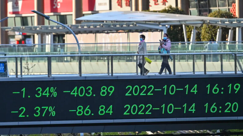 Un grupo de personas cruza un puente con un tablero indicador de acciones en el distrito financiero de Lujiazui, en Shanghái, el 17 de octubre de 2022. (Foto de HECTOR RETAMAL/AFP vía Getty Images)