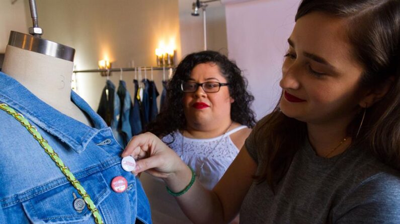 Diseñadoras de moda adornan una chamarra con chapitas en una de sus prendas en un taller de Los Ángeles, California. (EFE/Felipe Chacón)