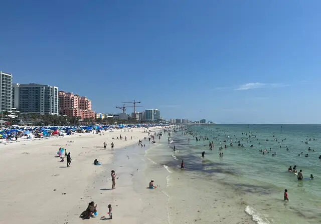 Turistas y lugareños juegan en las olas y la arena de Clearwater Beach, Florida, el 2 de julio de 2023. (Nanette Holt/The Epoch Times)