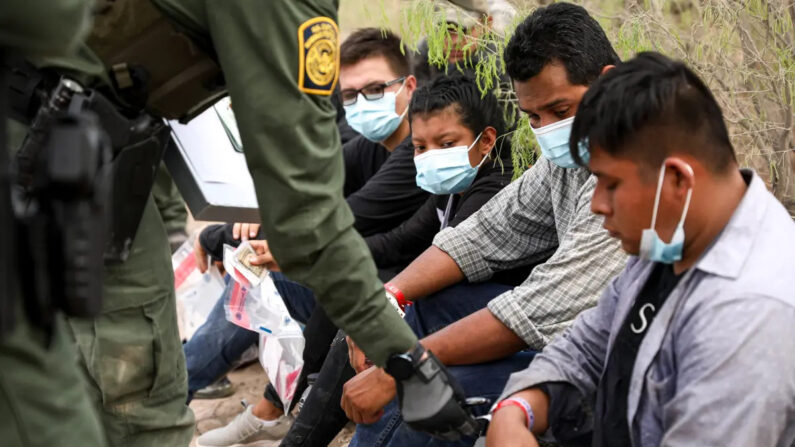 Un agente de la Patrulla Fronteriza revisa a un inmigrante ilegal que lleva dos pulseras que los cárteles mexicanos han estado utilizando para controlar el contrabando de personas hacia Estados Unidos, cerca de Peñitas, Texas, el 15 de marzo de 2021. (Charlotte Cuthbertson/The Epoch Times)