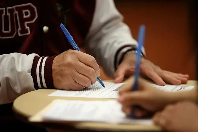 Varias personas firman formularios de empleo en una foto de archivo. (Justin Sullivan/Getty Images)