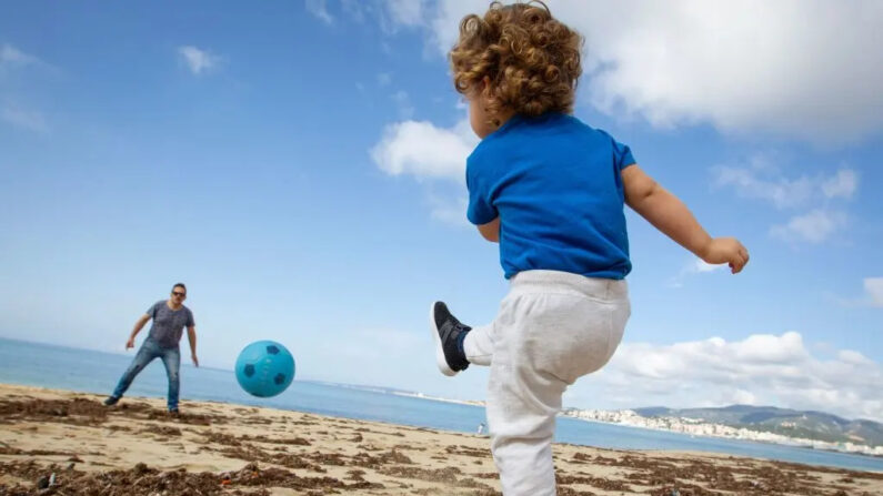 Un niño juega al fútbol con su padre en la playa de Can Pere Antoni en Palma de Mallorca, España, el 26 de abril de 2020. (Jaime Reina/AFP