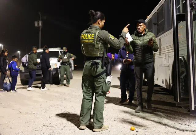 Un agente de la Patrulla Fronteriza gesticula mientras inmigrantes ilegales se preparan para abordar un autobús hacia un centro de procesamiento de la Patrulla Fronteriza de EE.UU. después de cruzar a Arizona desde México en Yuma, Arizona, el 11 de mayo de 2023. (Mario Tama/Getty Images)
