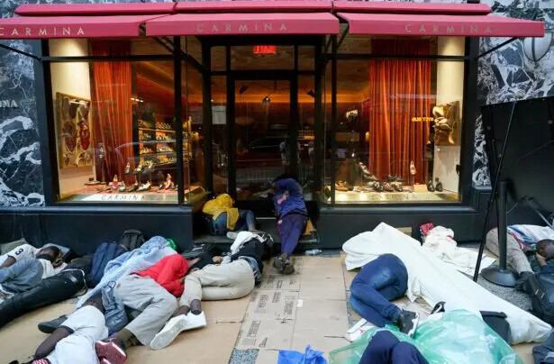 Inmigrantes ilegales duermen afuera del Hotel Roosevelt de nueva York, el 1 de agosto de 2023, mientras esperan ser ubicados en este establecimiento que funciona como albergue. (Timothy A. Clary/AFP vía Getty Images)