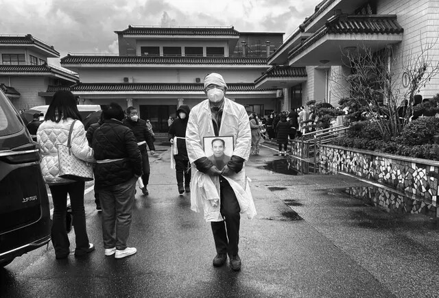 Un doliente lleva una foto de un ser querido mientras viste la tradicional ropa blanca fúnebre, en una funeraria, el 14 de enero de 2023 en Shanghai, China. (Kevin Frayer/Getty Images)
