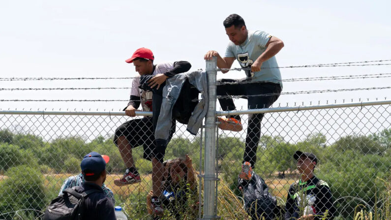 Inmigrantes ilegales saltan la cerca de alambre de púas hacia Estados Unidos desde México, en Eagle Pass, Texas, el 25 de agosto de 2023. (Suzanne Cordeiro/AFP vía Getty Images)
