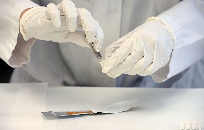 Un técnico de laboratorio en una imagen de archivo realiza pruebas para buscar muestras de restos de ADN. (BORIS HORVAT/AFP vía Getty Images)