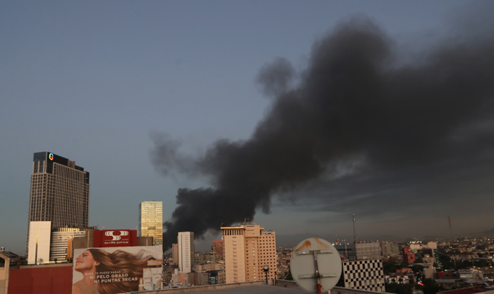 Fotografía de una columna de humo producto de un gran incendio este jueves, en la Ciudad de México, México. Una bodega de calzado en calles céntricas de capital mexicana fue consumida por el fuego sin que se registraran hasta el momento víctimas mortales este jueves; el siniestro provoco una gran columna de humo negro que podía observarse desde cualquier punto de la Ciudad de México. (EFE/Mario Guzmán)