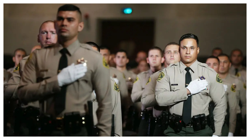 Graduados de la Academia del Departamento del Sheriff del Condado de Los Ángeles de pie para el juramento de lealtad en su ceremonia de graduación en East Los Angeles College en Monterey Park, California, el 21 de agosto del 2020. (Mario Tama/Getty Images)